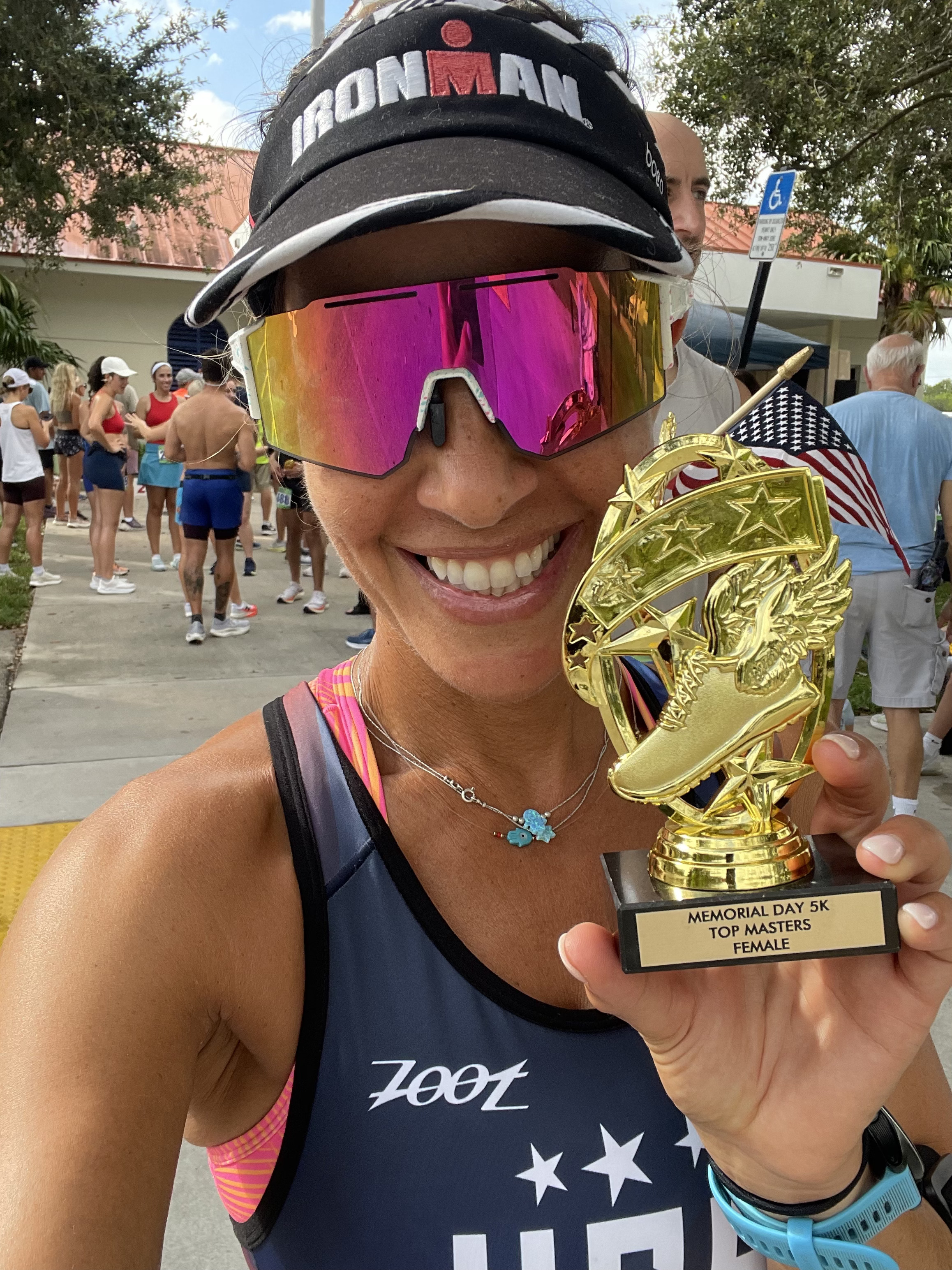 Dr. Hadar holding a Memorial Day 5K Top Masters Female trophy, wearing an Ironman visor