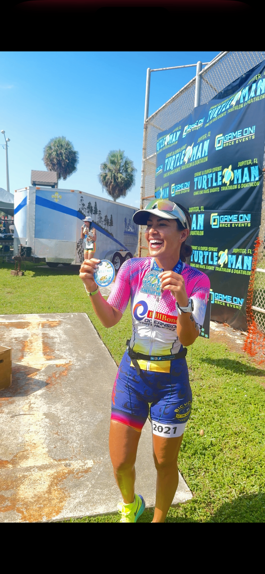 Dr. Hadar smiling at the Turtle Man Triathlon finish line holding her first-place age group medal